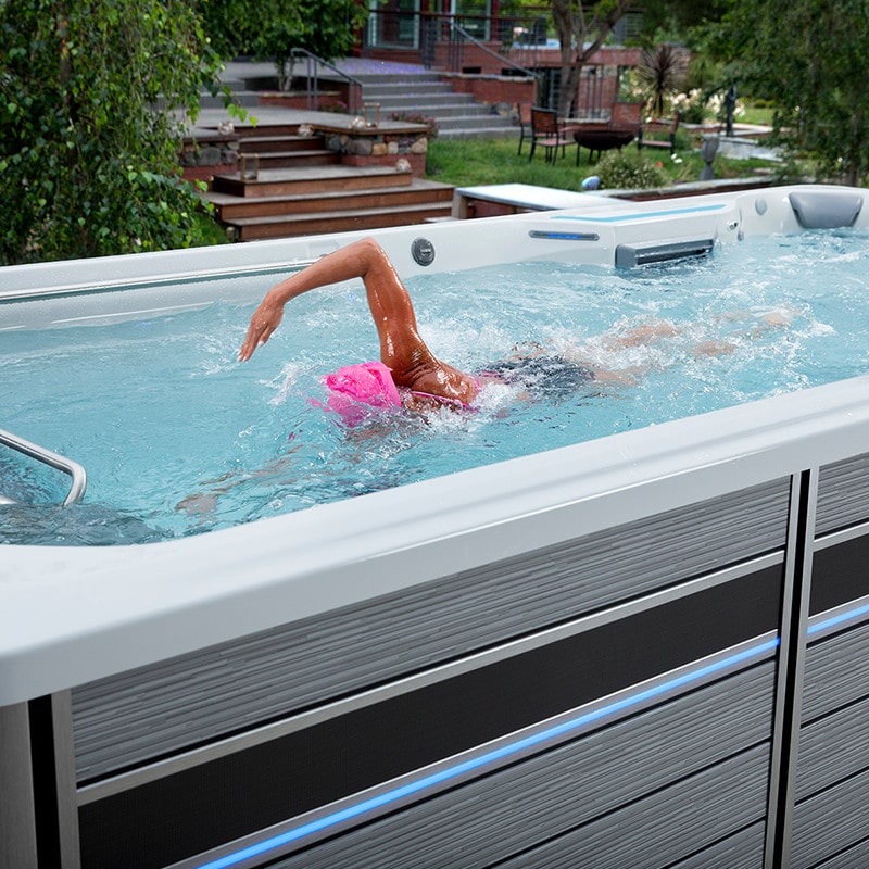 woman with pink swim cap practicing her freestyle stroke in endless pool