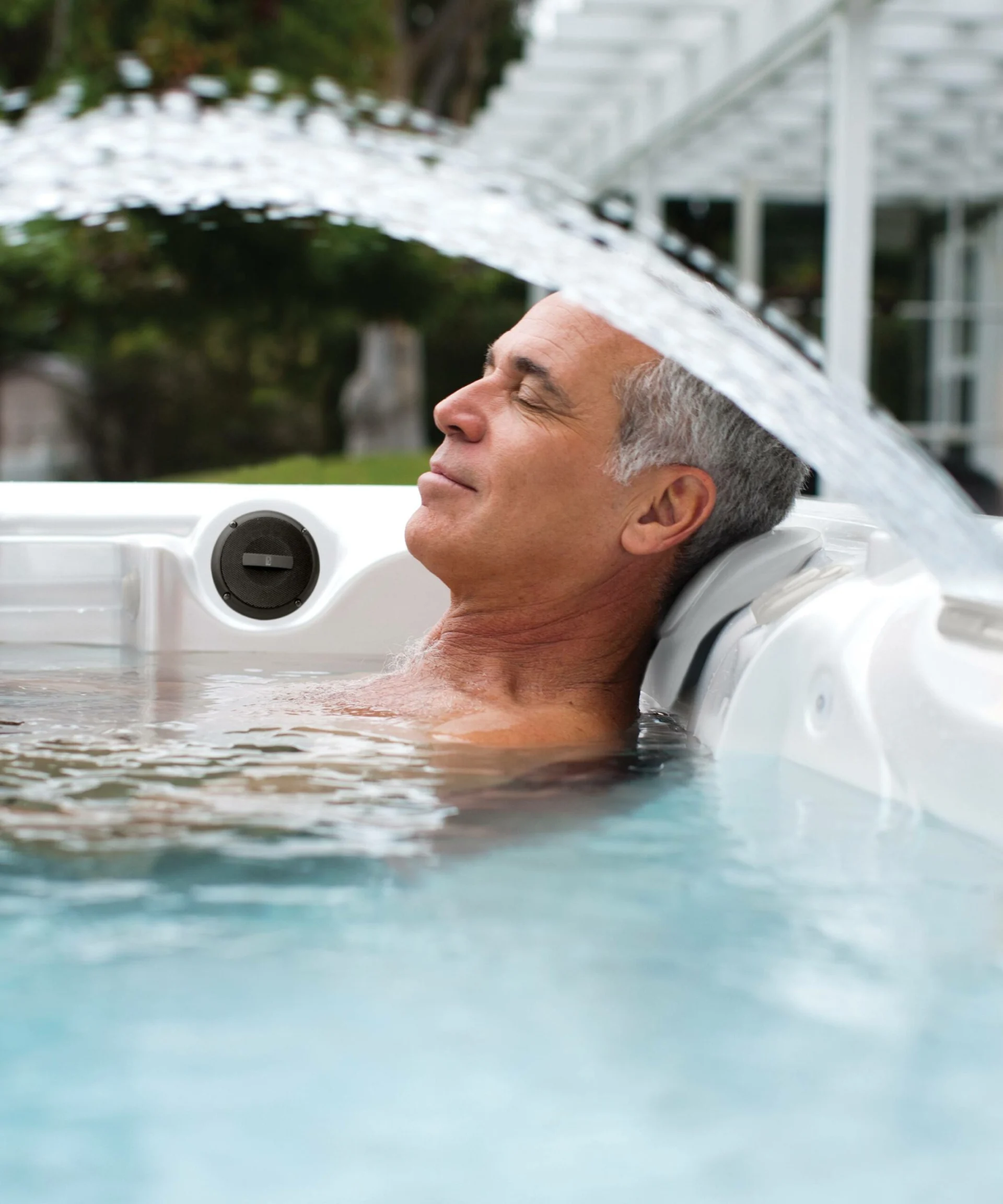 man relaxing peacefully in a hot tub with a water feature.