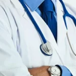 Doctor wearing a white lab coat, blue tie, and stethoscope.