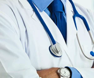 Doctor wearing a white lab coat, blue tie, and stethoscope.
